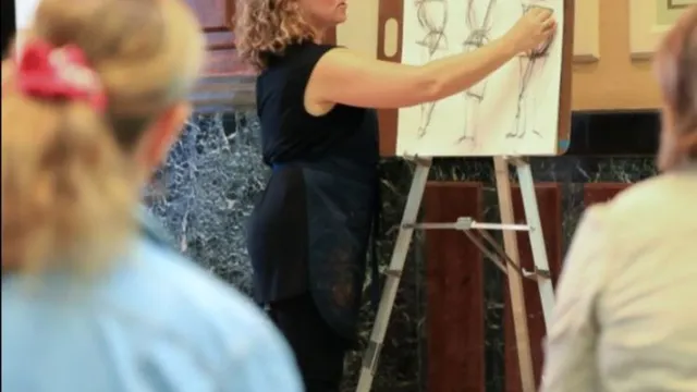 Jill drawing on an easel in front of a class