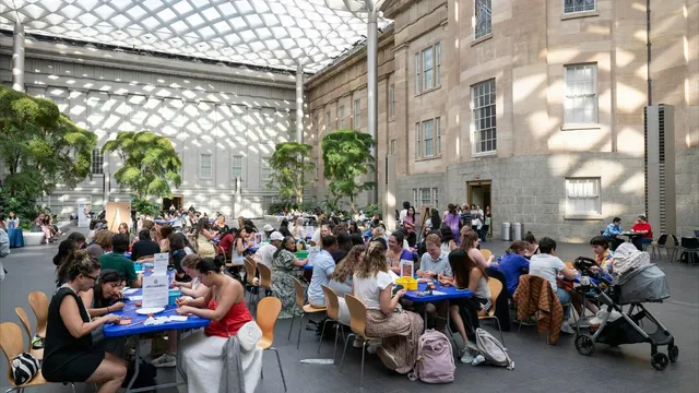 Visitors sitting at tables, crafting, and socializing in the Portrait Gallery's Kogod Courtyard.