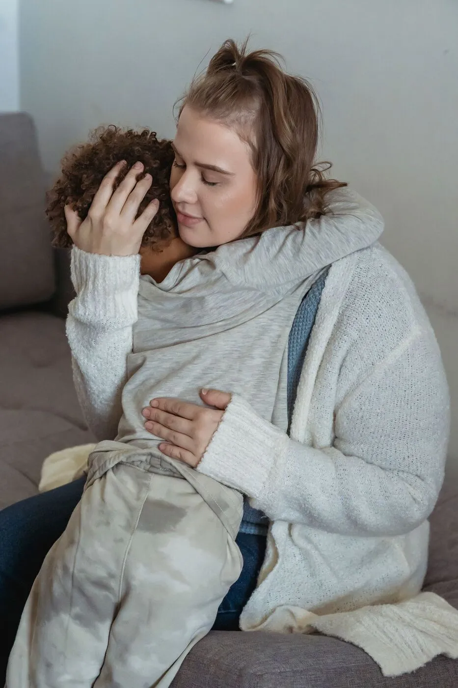 Una cuidadora abraza a un niño angustiado en un sofá.