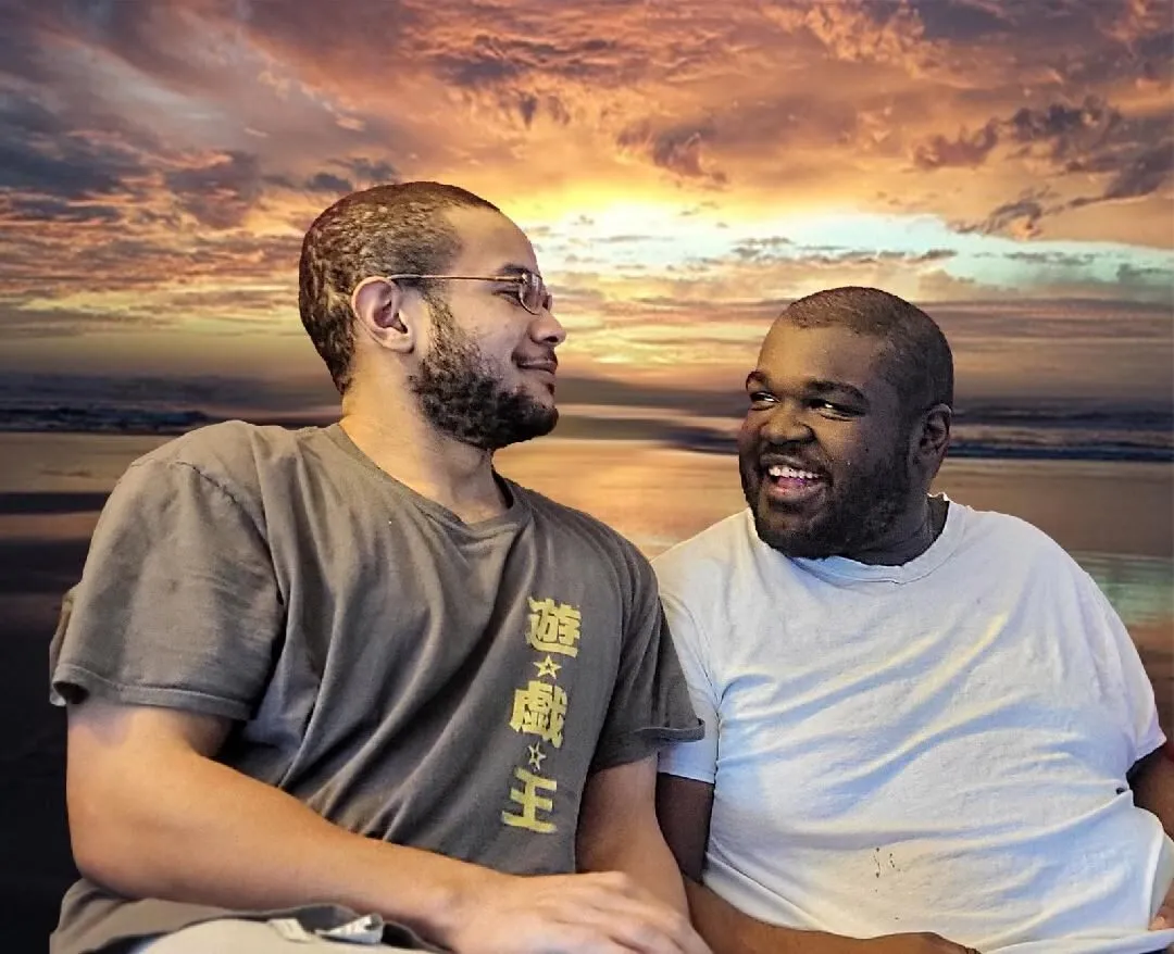 Brothers Joshua and Jahvah Jones sit together, smiling, against a sunset sky.