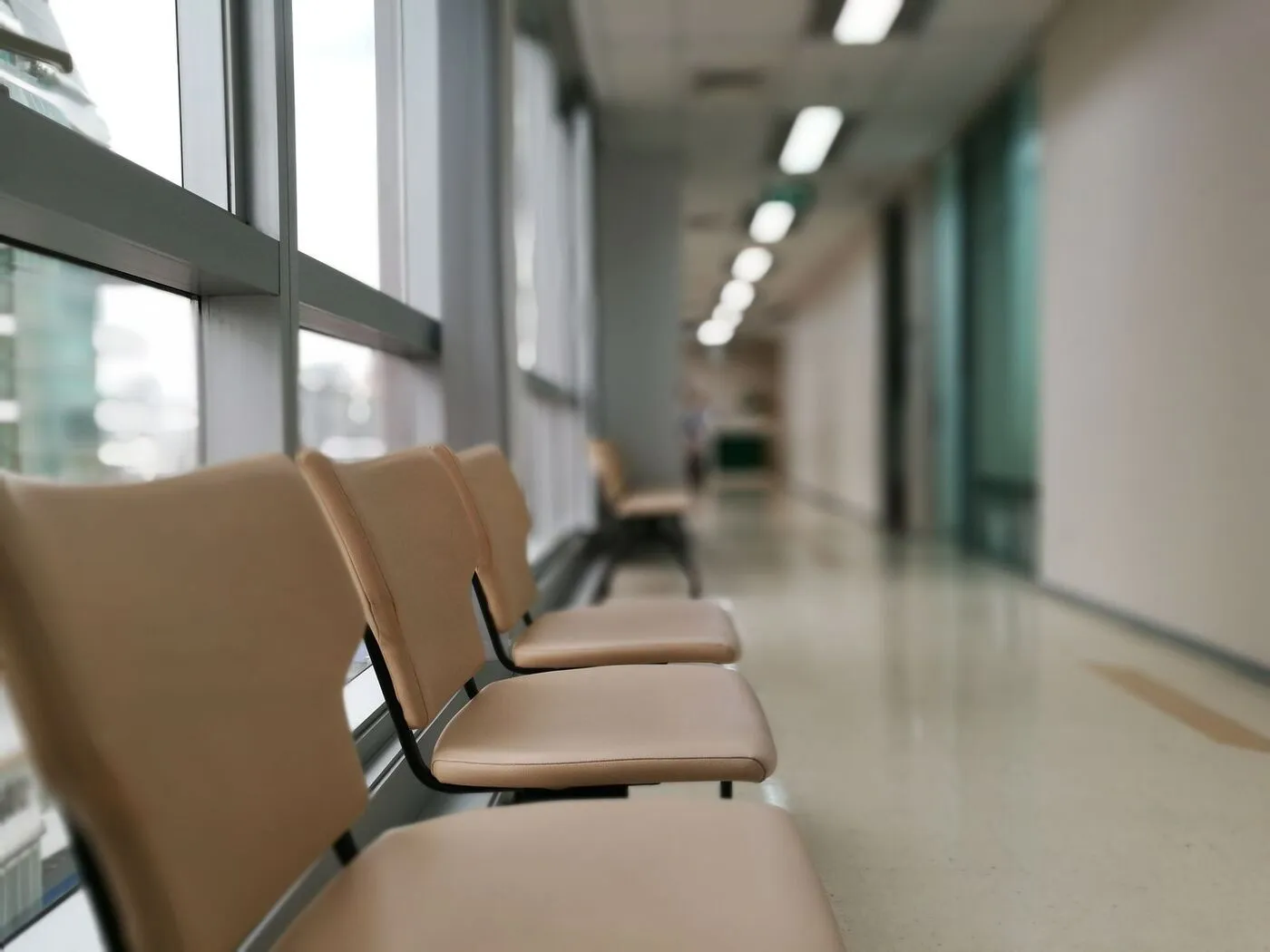 An empty hospital corridor lined with waiting chairs.