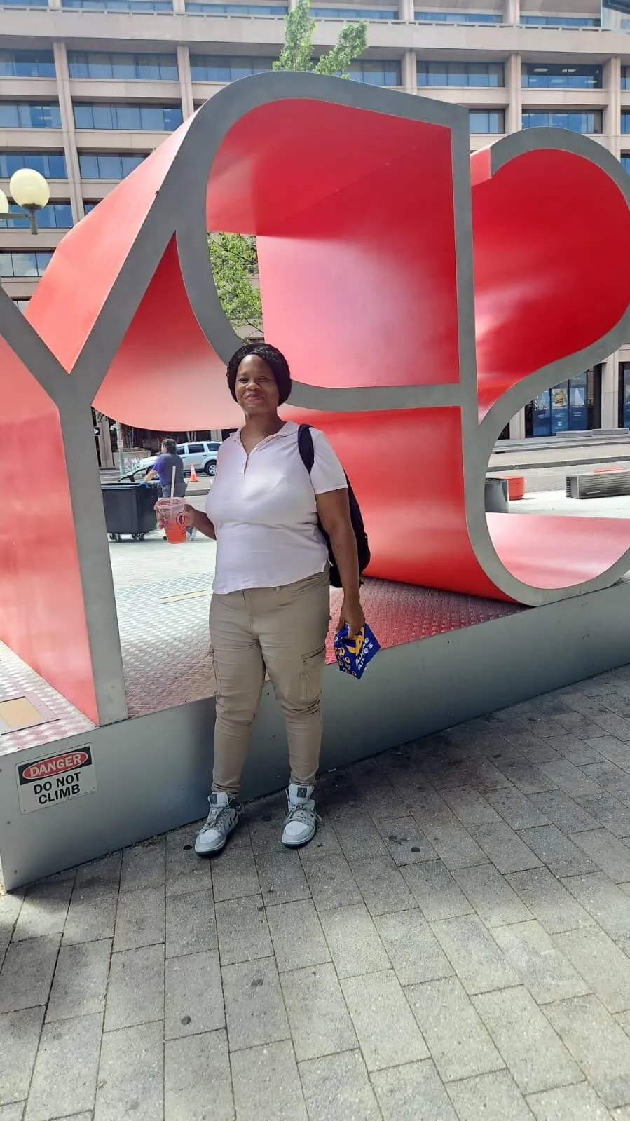 A woman stands inside a large red sculpture on a DC plaza during a community outing.
