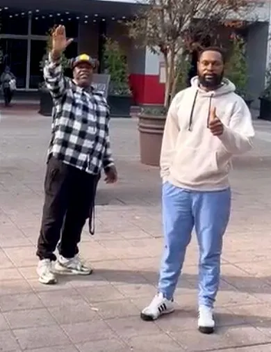 Nelson waves beside Jerimah on a city sidewalk.