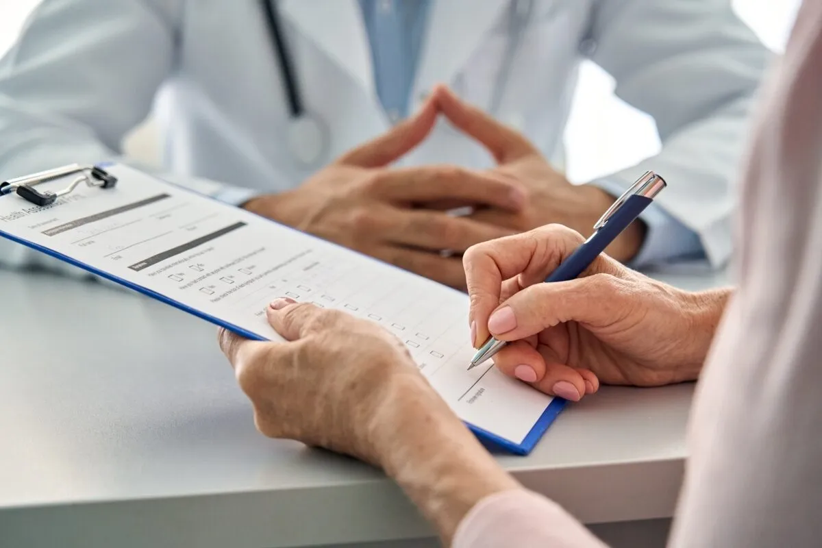 Two people review and sign a form on a clipboard.