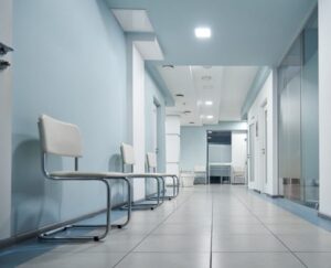 An empty clinic corridor lined with waiting chairs.
